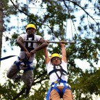 Bright Wokocha and Adam Conoley hang onto a swing, breathless from climbing up a tall wooden pole and jumping out to reach the swing. (Photo: Travis Short)