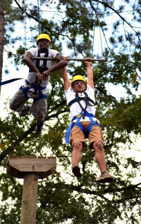 Bright Wokocha and Adam Conoley hang onto a swing, breathless from climbing up a tall wooden pole and jumping out to reach the swing. (Photo: Travis Short)