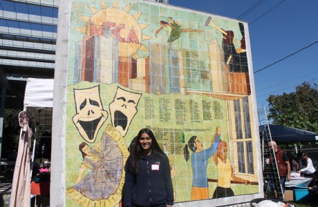 SNHS President Shivani Raman poses in front of a MECA mosaic mural at the Dia de Los Muertos Festival.