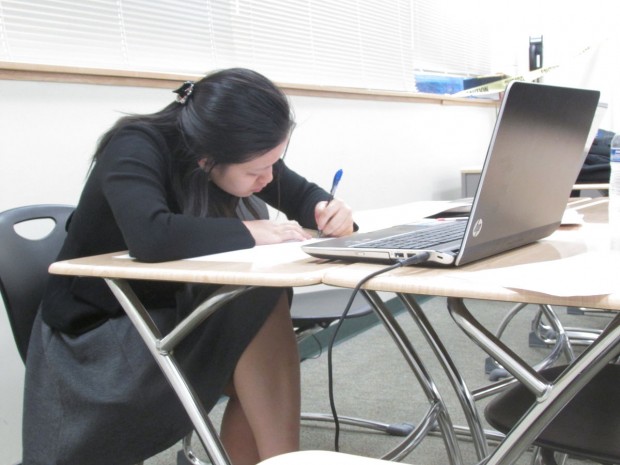 Liana Wang writes out responses to arguments while the other team gives their speech; she does Cross-Examination debate. 