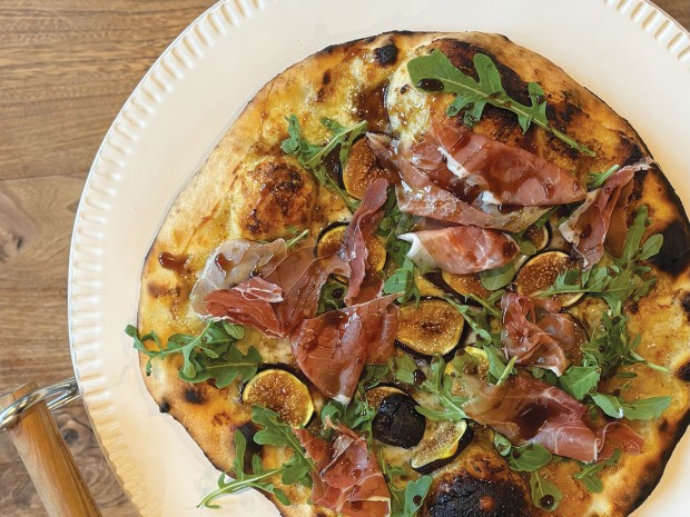 Pizza topped with fig preserves, fontina, figs, prosciutto, and arugula