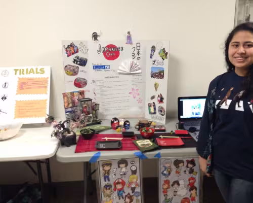 Aileen Martinez (junior) poses by her club poster decorated with Japanese elements and anime.